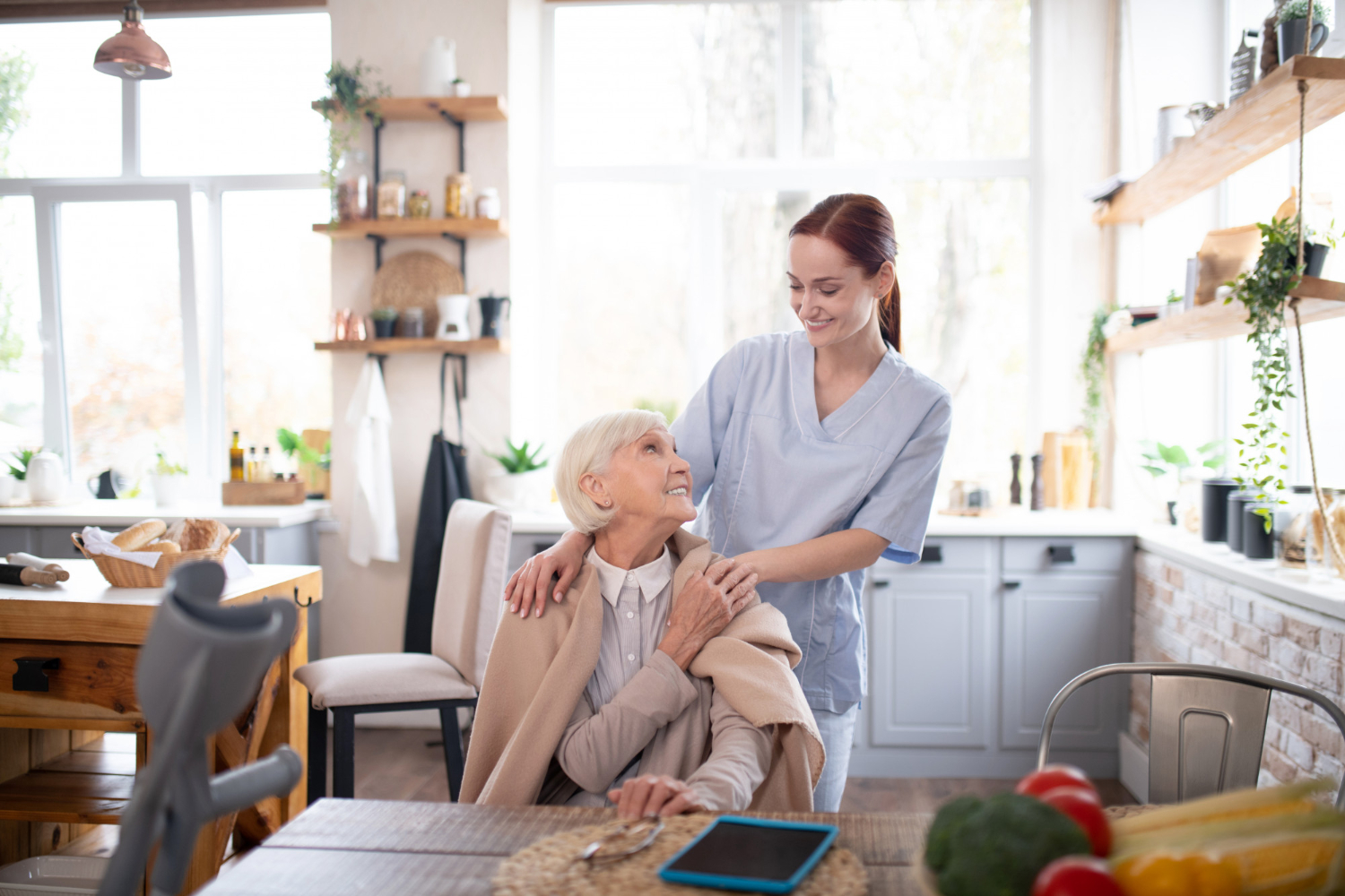 Betreuungskraft unterstützt eine Seniorin in der Küche